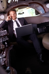 Handsome young businessman sitting in limousine, talking on mobi